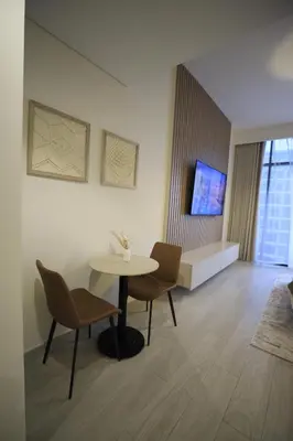 a living room with a table and chairs and a tv at Modern and cozy studio apartment in Dubai