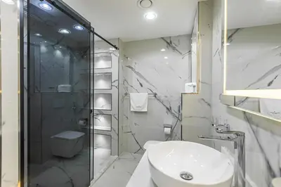 a white bathroom with a shower and a sink at Spacious 2 BDR apartment in Downtown Dubai I 29 Blvd in Dubai