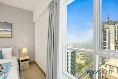 a bedroom with a large window with a view of a city at Salt & Sand Hamptons Glow 2BR Sulafa Tower in Dubai