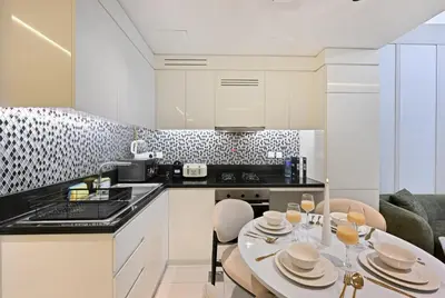 a kitchen with a table and chairs and a kitchen with white cabinets at High Floor 2 Bedroom Apartment - Exclusive Luxury at Aykon Tower - PlayStation 5 in Dubai