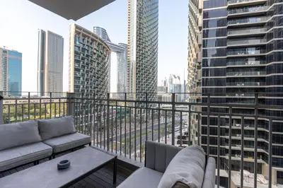 a balcony with a couch and a table and some buildings at Newly Upgraded 2BR - Steps from Burj Khalifa and Opera in Dubai