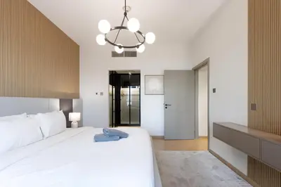 a bedroom with a large white bed and a chandelier at Newly Upgraded 2BR - Steps from Burj Khalifa and Opera in Dubai