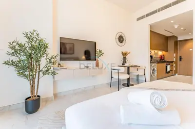 a white living room with a large bed and a tv at Just Minutes Drive From Dubai Autodrome, Conveniently Located Within A Short Walk Of The Bus Stop, Azizi Vista, Dubai Studio City by Deluxe Holiday Homes in Dubai