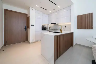a kitchen with white walls and wooden cabinets at High Floor JVC 1BR Skyline Showstopper in Dubai