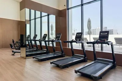 a row of treadmills in a gym with windows at High Floor JVC 1BR Skyline Showstopper in Dubai