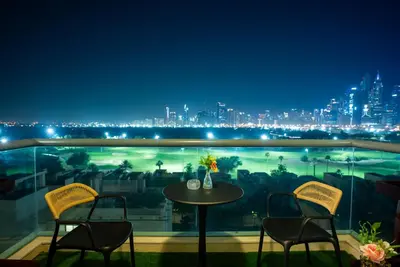 a table and chairs on a balcony with a city skyline at Luxury 2BR Haven with Panoramic Scenery in Dubai