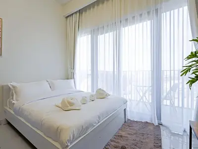 a bedroom with a bed with white sheets and a large window at Elegant Modern Studio- Peaceful Studio City in Dubai