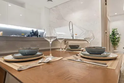 a table with two wine glasses and plates on it at FIRST CLASS 1BR Burj Views , Prime Location in Dubai