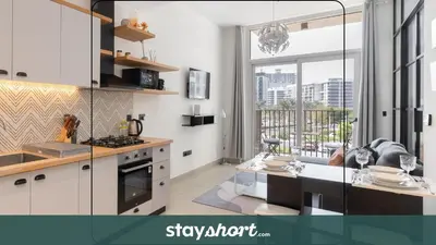 a kitchen with white cabinets and a large window at StayShort - Modern Dubai Hills Apartment Great Pool Sleeps 4 in Dubai