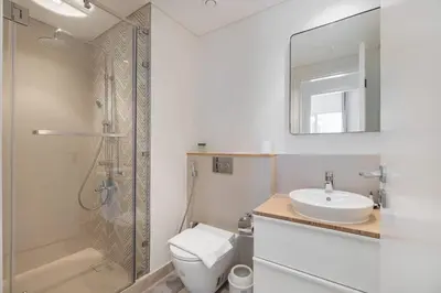 a bathroom with a toilet and a sink and a shower at StayShort - Modern Dubai Hills Apartment Great Pool Sleeps 4 in Dubai