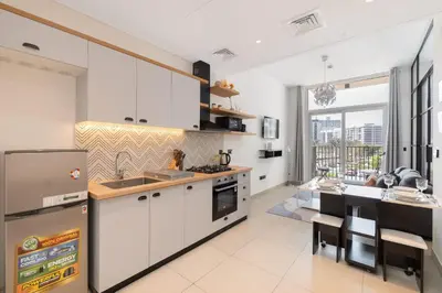 a kitchen with white cabinets and a large window at StayShort - Modern Dubai Hills Apartment Great Pool Sleeps 4 in Dubai