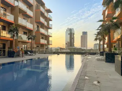 a large swimming pool with palm trees and buildings at FIRST CLASS 1BR Tranquil Pool View Retreat in Dubai