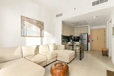 a living room with a white couch and a kitchen at FIRST CLASS 1BR Tranquil Pool View Retreat in Dubai