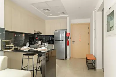 a kitchen with a counter with chairs and a refrigerator at FIRST CLASS 1BR Tranquil Pool View Retreat in Dubai
