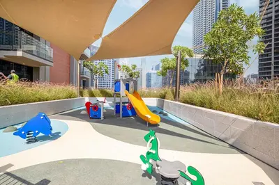 a playground with a slide in a building with tall buildings at Lux 1BR with Stunning Canal Views in Dubai