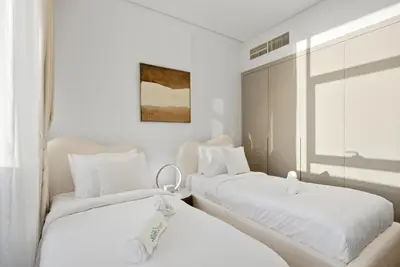 two beds in a room with white walls at Chic 2Bedroom with Exceptional Facilities in JVC in Dubai