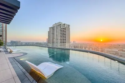 a swimming pool on top of a building with a sunset at Chic 2Bedroom with Exceptional Facilities in JVC in Dubai