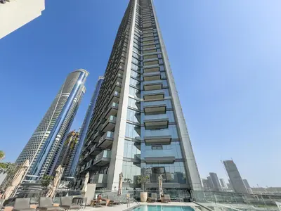 a tall building with a pool in front of two tall buildings at Luxury 1BR in Nobles Tower - Business Bay Skyline in Dubai