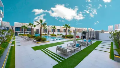 a resort with a pool and chairs and palm trees at Luxurious Cozy Studio with Balcony Pool & Gym in Dubai
