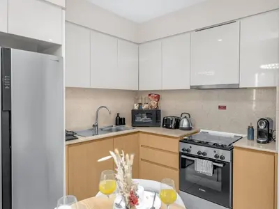 a kitchen with white cabinets and a table with wine glasses at Luxury 2BHK with view of Burj Khalifa & Fountain in Dubai