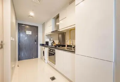 a white kitchen with a sink and a dishwasher at Serene Golf Course Studio in Artesia Damac Hills in Dubai Marina