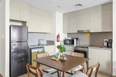 a kitchen with a table with chairs and a refrigerator at Silkhaus Stylish 1BDR with Pool & Balcony Dubai Creek Harbour in Dubai