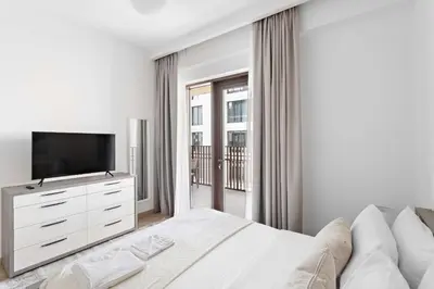 a white bedroom with a bed and a television at Silkhaus Stylish 1BDR with Pool & Balcony Dubai Creek Harbour in Dubai
