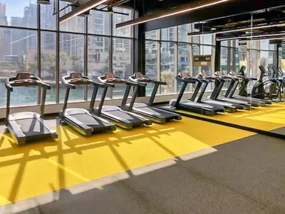 a row of treadmills in a gym with windows at Stylish Deluxe Two Bedrooms In Dubai Marina in Dubai