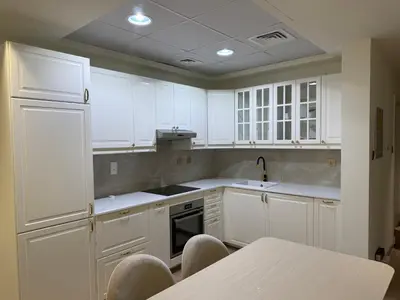 a kitchen with white cabinets and a table and chairs at Heart of Marina with Free Parking, Pool and Gym in Dubai