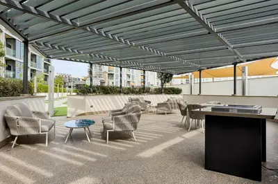 a patio with chairs and tables on a building at 1B with Park and Burj Khalifa View, Hartland Waves in Dubai