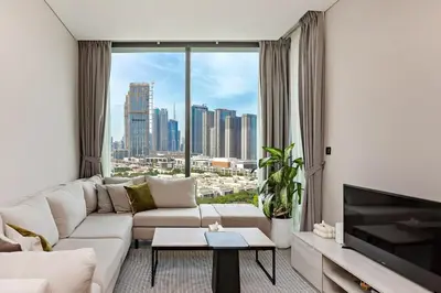 a living room with a white couch and a large window at 1B with Park and Burj Khalifa View, Hartland Waves in Dubai