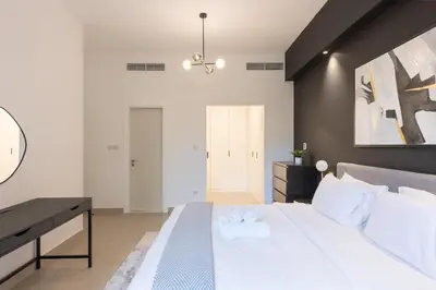 a bedroom with a large white bed and a desk at Spacious 3BR with Large Terrace in Dubai