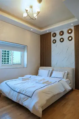 a large white bed in a bedroom with a chandelier at 902, Royal Residencies, Dubai Sports City in Dubai