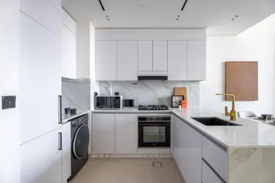 a white kitchen with white cabinets and appliances at GuestReady - Cozy Stay | Near Parks | JVC in Dubai