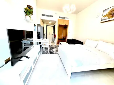 a white bedroom with a white bed and a dining room at Skyz by Danube, Brand new Studios in Arjan in Dubai