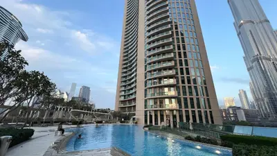 a large building with a swimming pool next to a tall building at Burj Vista! Great High Floor View! Mall Connected! Amazing Pool, Gym and Location! in Dubai