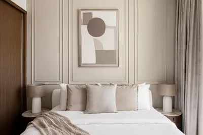 a bedroom with a bed with white pillows and a painting at Beachfront 1BR with Private Beach Access Renovated in Dubai