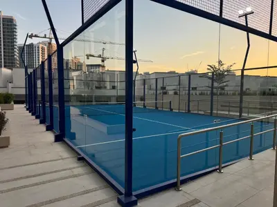 a tennis court on a building with glass walls at Modern and Serene Studio - JVC in Dubai