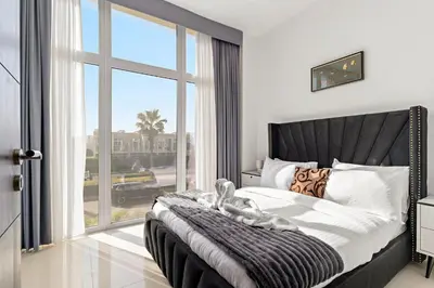 a bedroom with a large bed with a large window at Stylish Community 2BR Avencia 2,DAMAC Hills-2 in Dubai