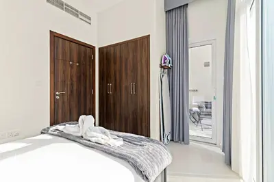a bedroom with a bed and a wooden closet at Stylish Community 2BR Avencia 2,DAMAC Hills-2 in Dubai
