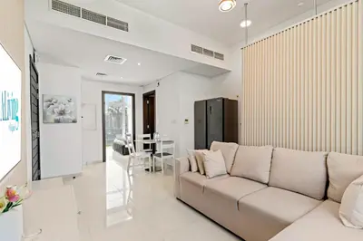 a living room with a couch and a table at Stylish Community 2BR Avencia 2,DAMAC Hills-2 in Dubai