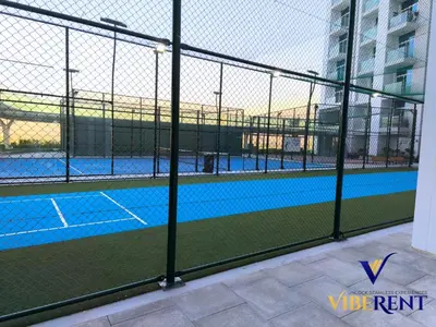 a tennis court seen through a chain link fence at Skyz by Danube Studio Dubai in Dubai