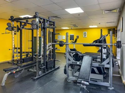a gym with several tread machines and a yellow wall at Chic Studio Near Circle Mall & Dubai Sports City in Dubai