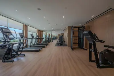a gym with a row of treadmills and machines at Refined Luxury 1BR Binghatti Azure in Dubai