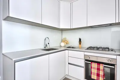 a white kitchen with white cabinets and a sink at Frank Porter - Luma 21 in Dubai