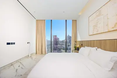 a white bedroom with a large bed and a large window at Stylish 4BR Penthouse with Maids Room & Modern Amenities in Dubai