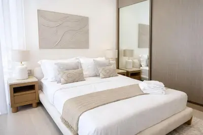 a white bedroom with a large bed and two tables at Chic 1BR Urban Retreat Binghatti Phantom in Dubai