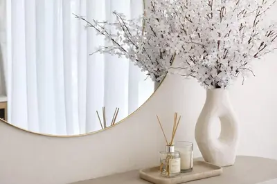 a white vase with flowers on a table with a mirror at Chic 1BR Urban Retreat Binghatti Phantom in Dubai
