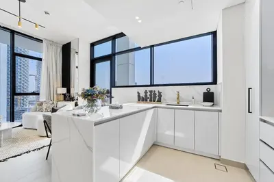 a kitchen with white cabinets and a large window at Elegant 2BR Apartment with Private Pool in JVC in Dubai