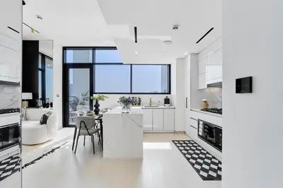 a kitchen with white cabinets and a dining room at Elegant 2BR Apartment with Private Pool in JVC in Dubai
